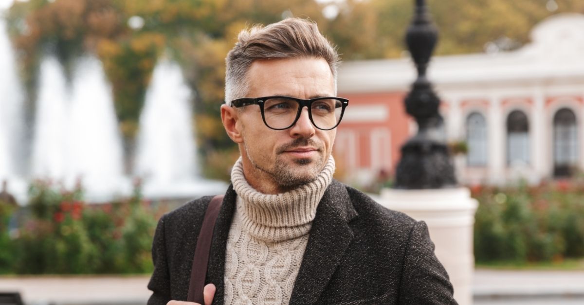A képen egy elegáns férfi látható szögletes keretű szemüvegben