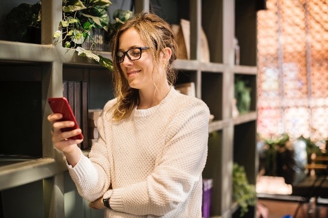Egy nő a telefonját nézi, ezzel is kékfény jut a szemébe